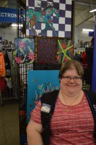 Goodwillians Rock at IDPD Talent Show 5 Carol Rousch artist paintings exhibited behind her